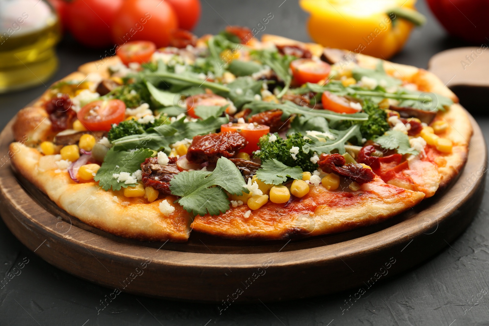 Photo of Delicious vegetarian pizza with cheese, vegetables and greens on black table, closeup