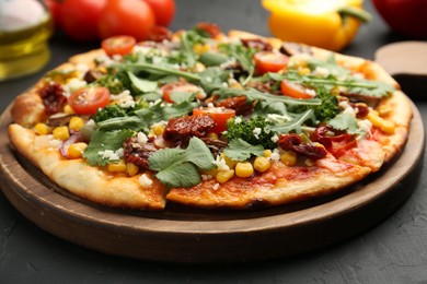 Photo of Delicious vegetarian pizza with cheese, vegetables and greens on black table, closeup