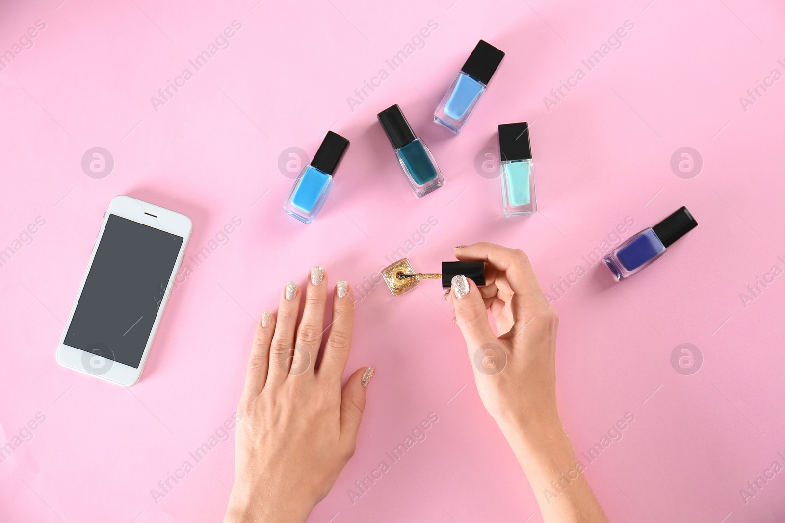 Photo of Woman applying nail polish on color background, top view