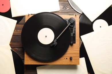 Vintage vinyl records and turntable on wooden background, flat lay