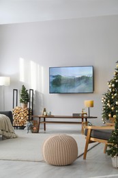 Photo of Modern TV set on light wall in room decorated for Christmas