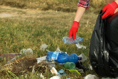 Photo of Woman in gloves with trash bag collecting garbage in nature, closeup