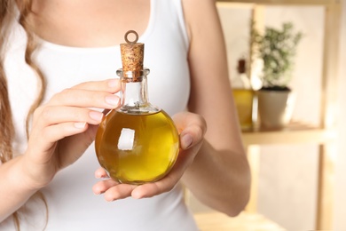 Young woman holding bottle of fresh olive oil, closeup