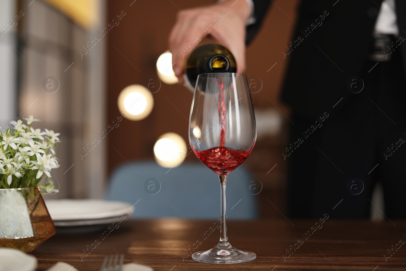 Photo of Man pouring wine into glass on table