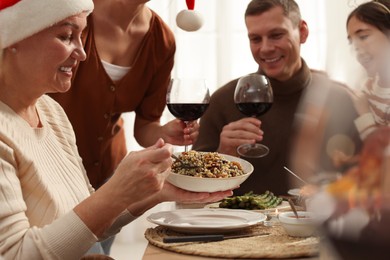 Photo of Woman with bowl of traditional Christmas slavic dish kutia and her family at festive dinner