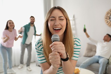 Photo of Young woman singing karaoke with friends at home