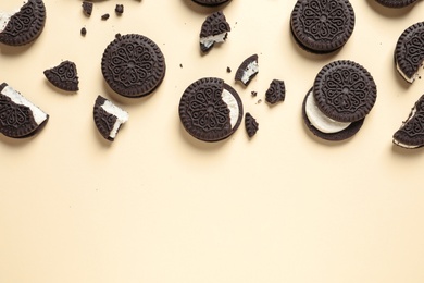 Photo of Tasty chocolate cookies with cream on color background, flat lay. Space for text