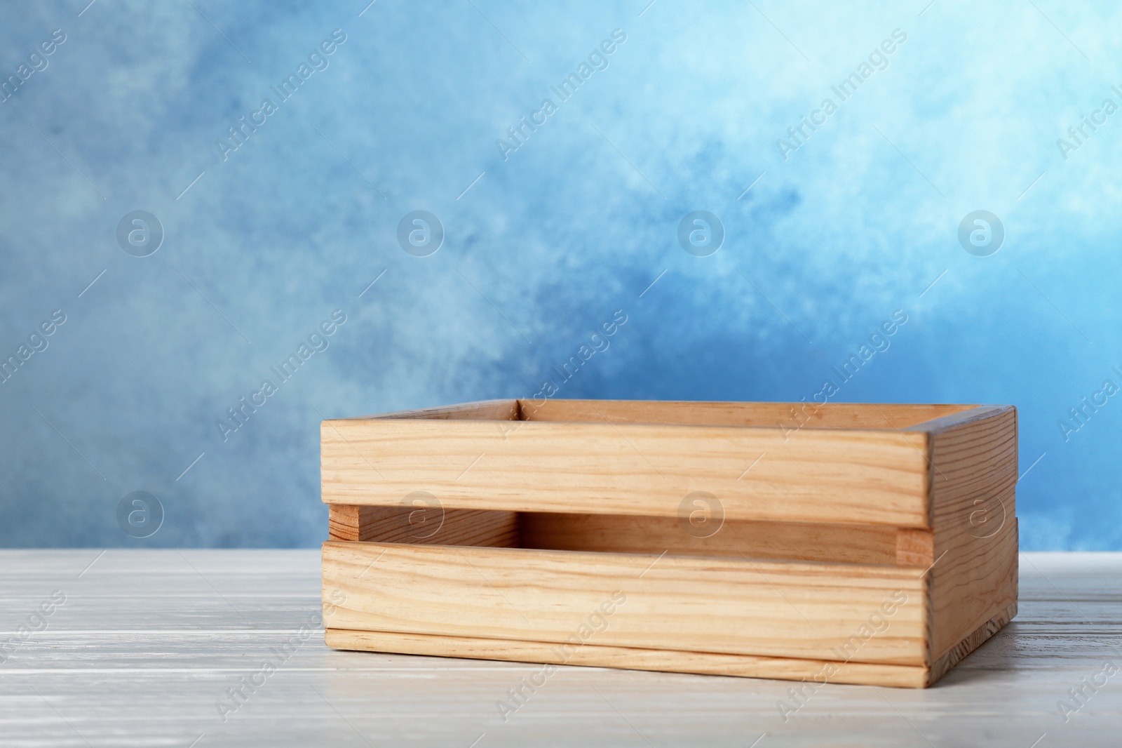 Photo of Wooden crate on table against color background. Space for text