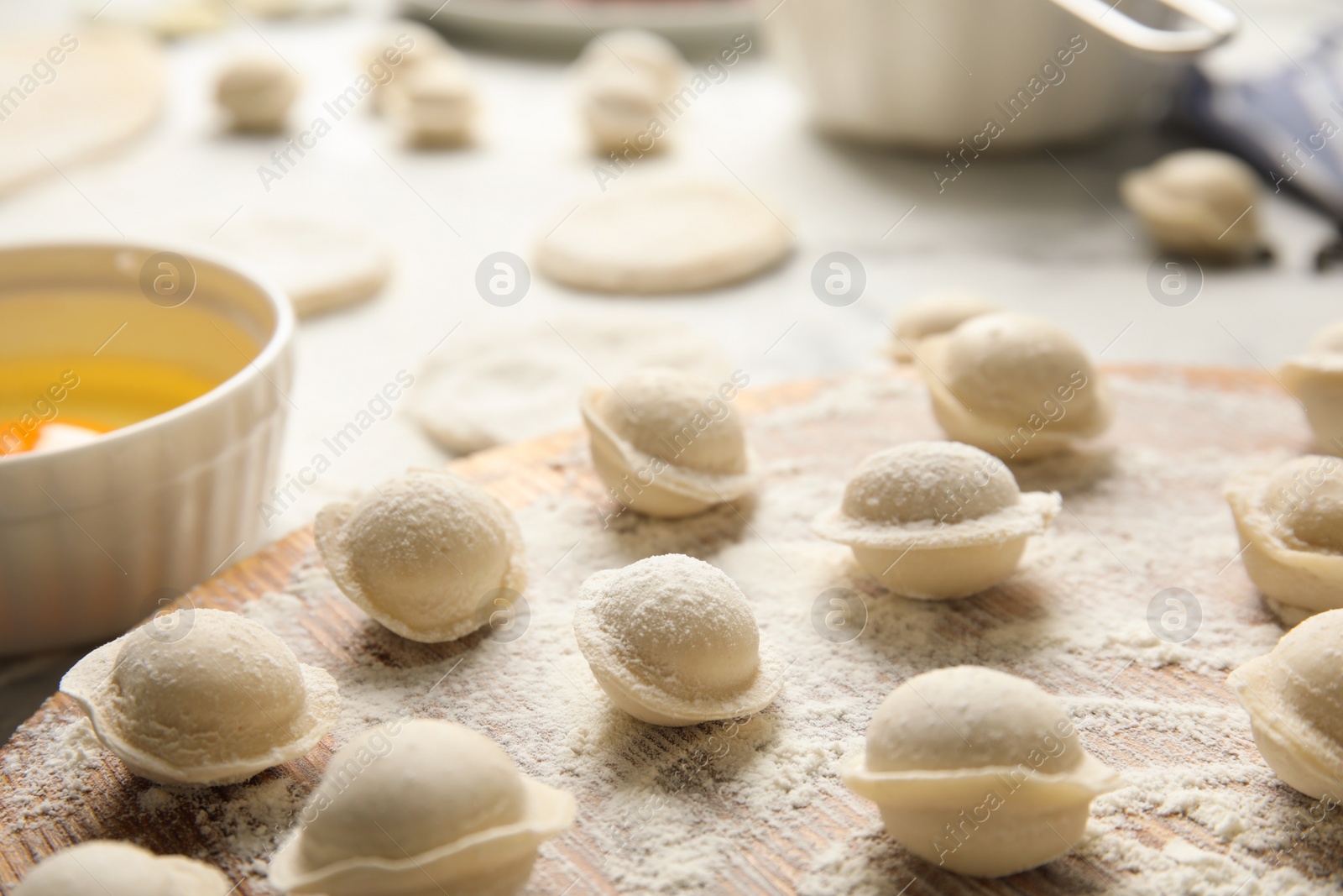 Photo of Raw dumplings on wooden board, closeup. Process of cooking
