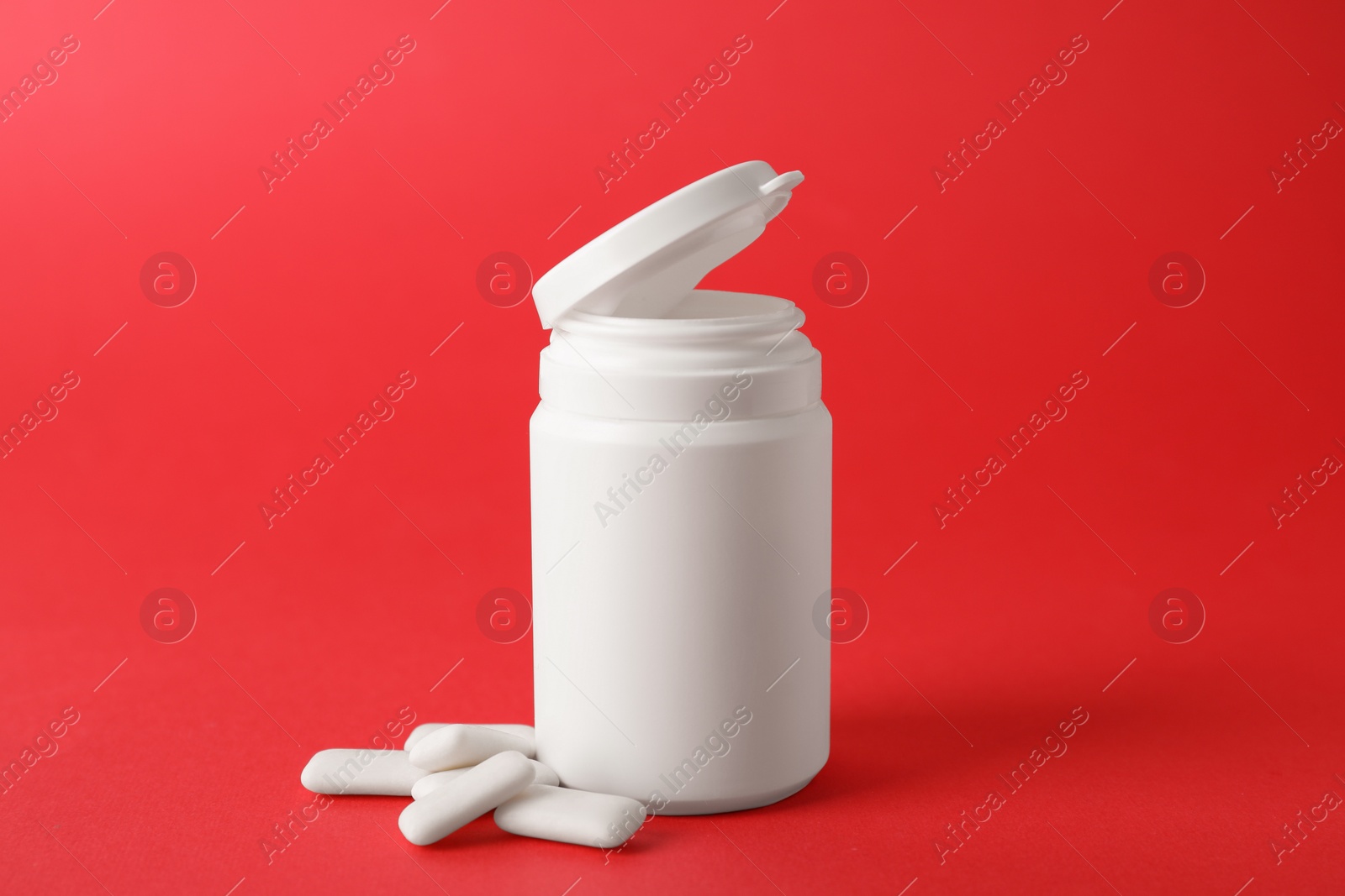 Photo of Jar with chewing gums on red background