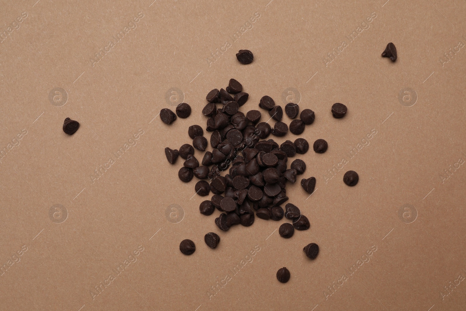 Photo of Pile of delicious chocolate chips on brown background, top view