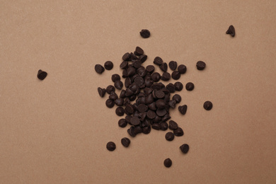 Photo of Pile of delicious chocolate chips on brown background, top view