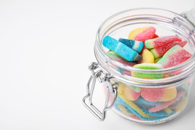 Tasty jelly candies in open jar on white table, closeup. Space for text