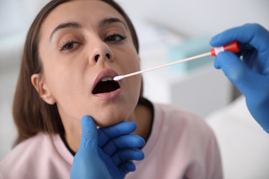 Doctor taking sample for DNA test from woman in clinic