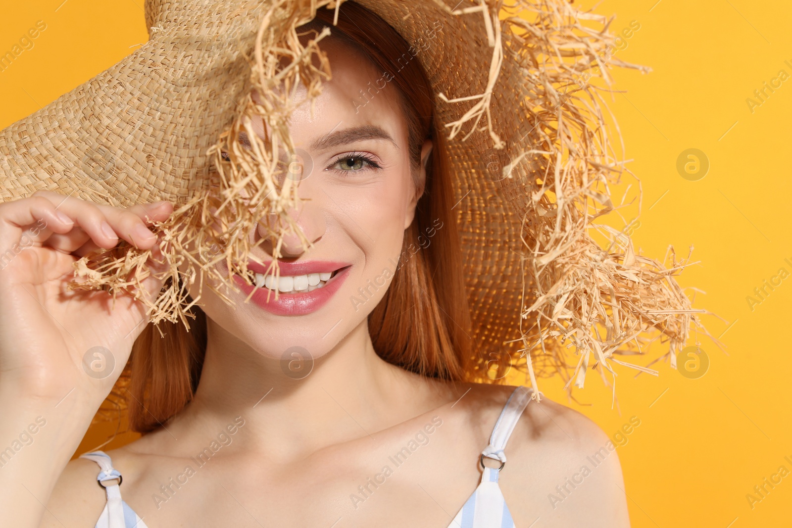 Photo of Beautiful young woman in straw hat on orange background