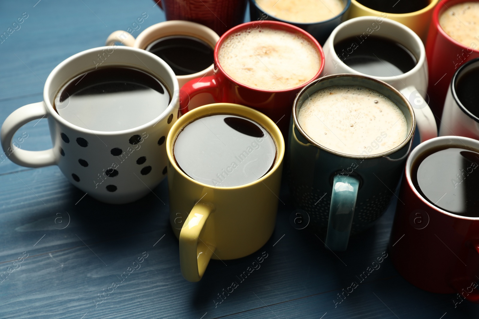 Photo of Many cups of different coffee drinks on blue wooden table