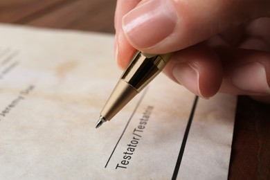 Photo of Woman signing Last Will and Testament at table, closeup