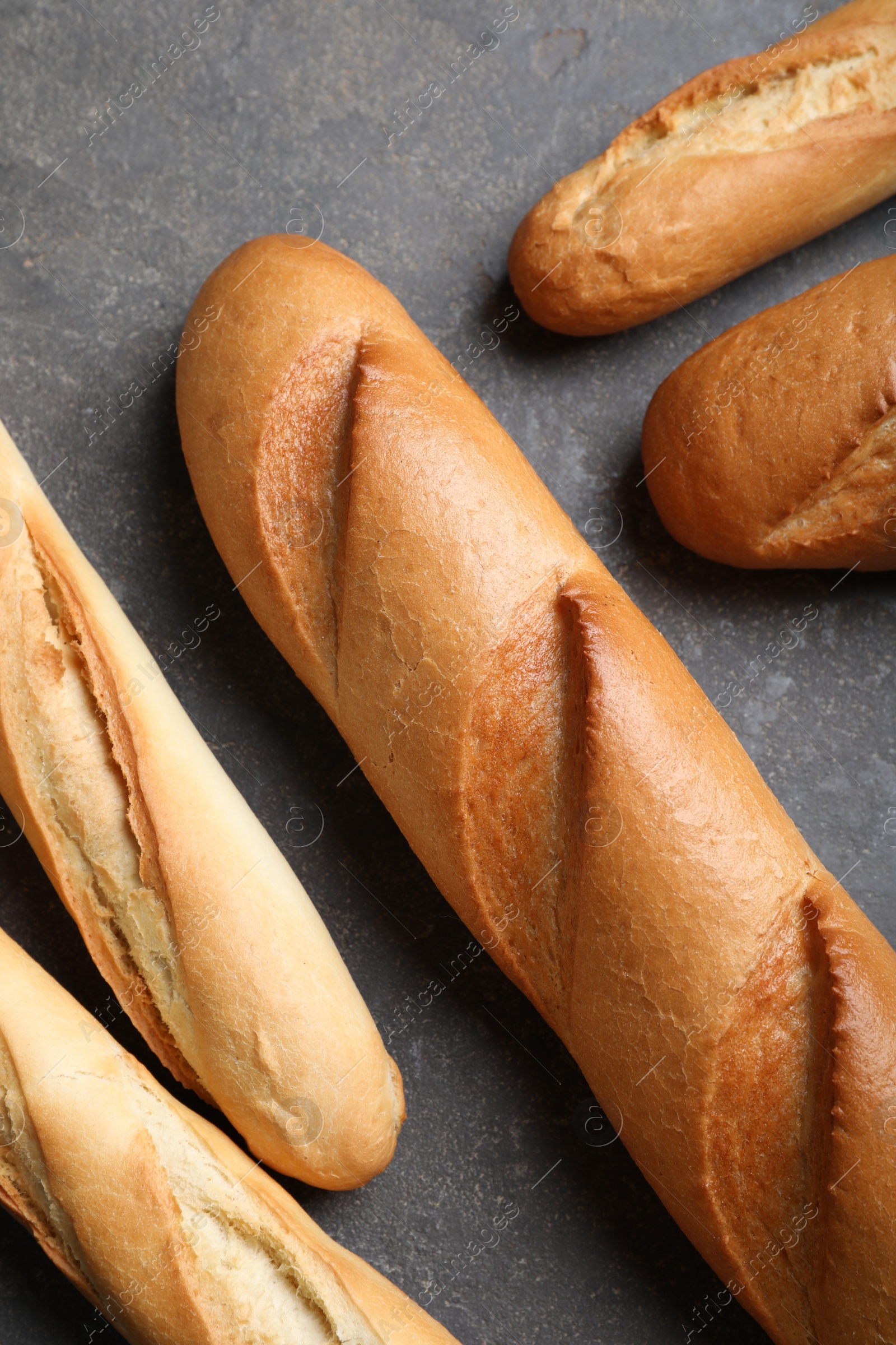 Photo of Different tasty baguettes on grey table, flat lay