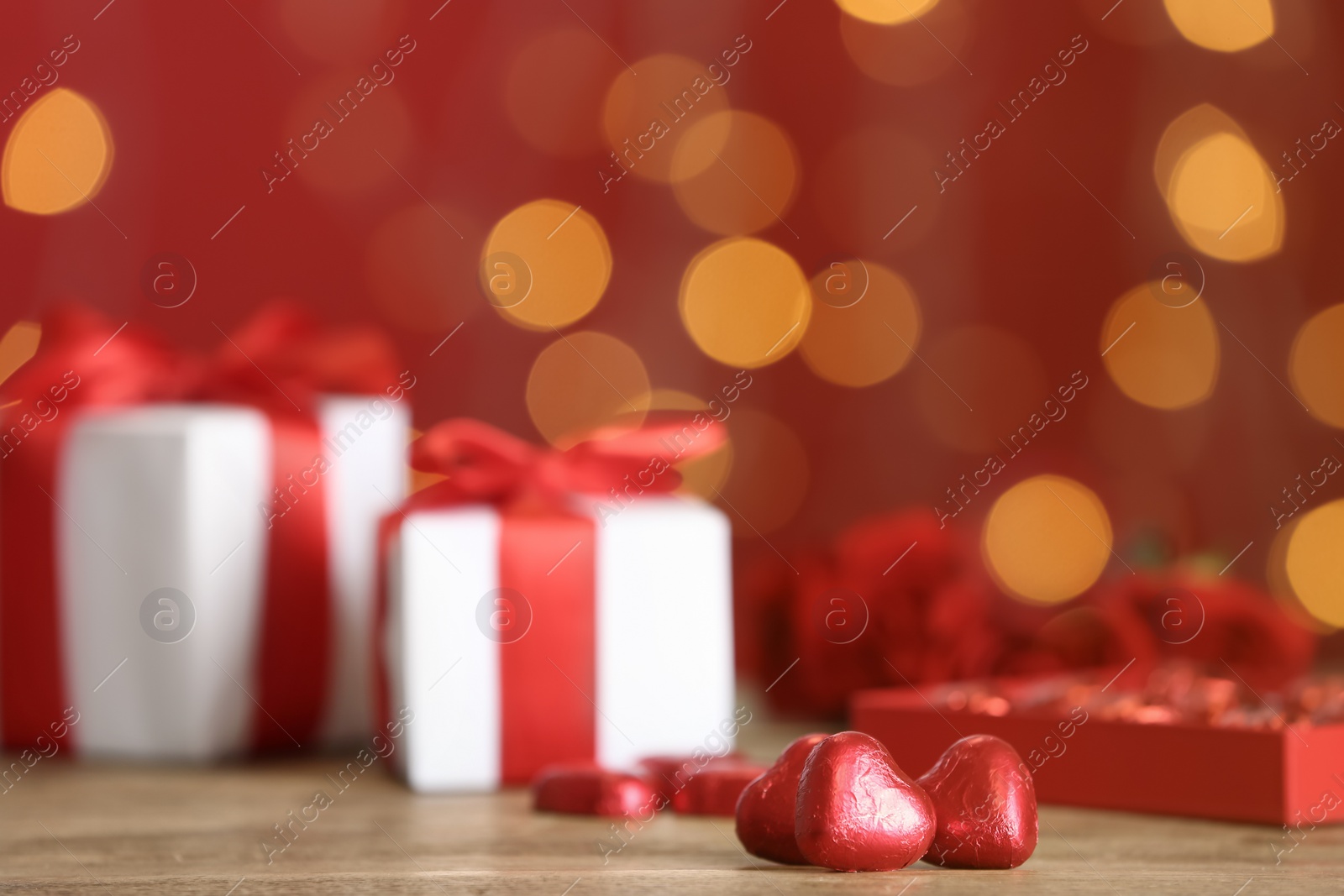 Photo of Heart shaped chocolate candies on table against blurred lights, space for text. Valentines's day celebration