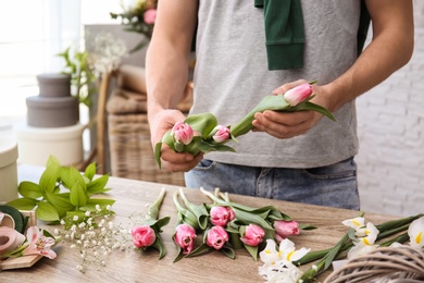 Photo of Male decorator creating beautiful bouquet at table