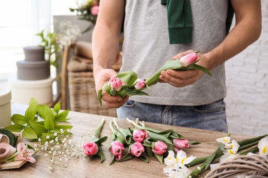 Male decorator creating beautiful bouquet at table