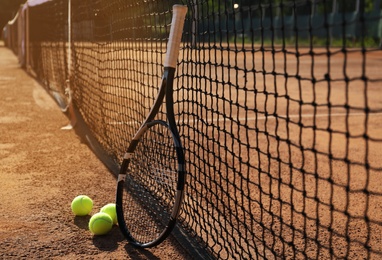 Tennis balls and racket on clay court