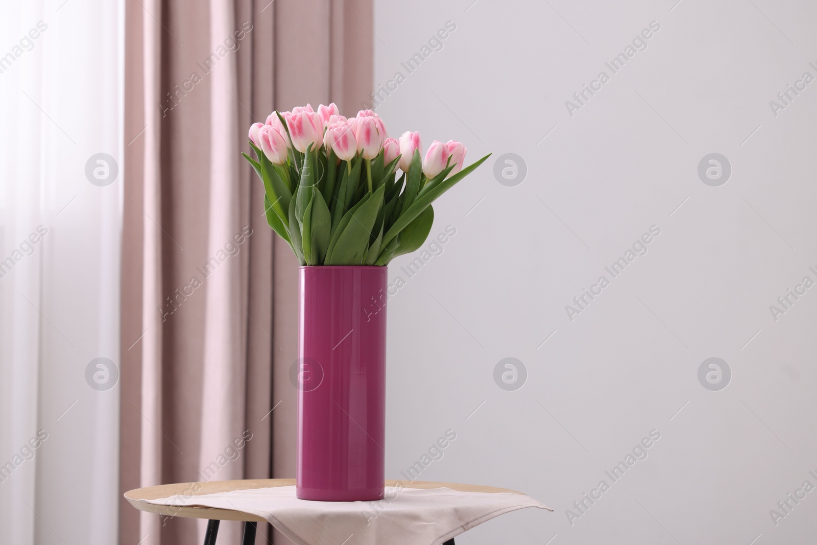 Photo of Beautiful bouquet of fresh pink tulips on table indoors. Space for text