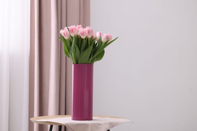 Photo of Beautiful bouquet of fresh pink tulips on table indoors. Space for text