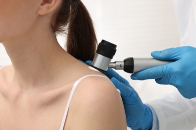 Photo of Dermatologist with dermatoscope examining patient in clinic, closeup