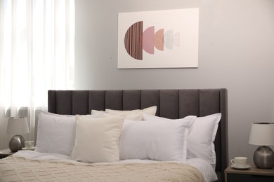 Photo of Many soft white pillows and knitted blanket on bed indoors