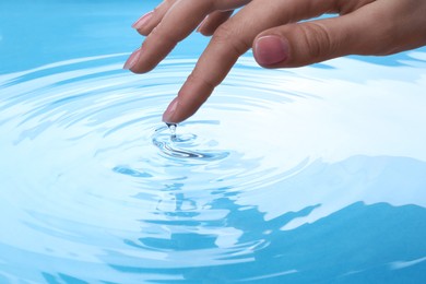 Photo of Woman touching clear water, closeup. Making ripples