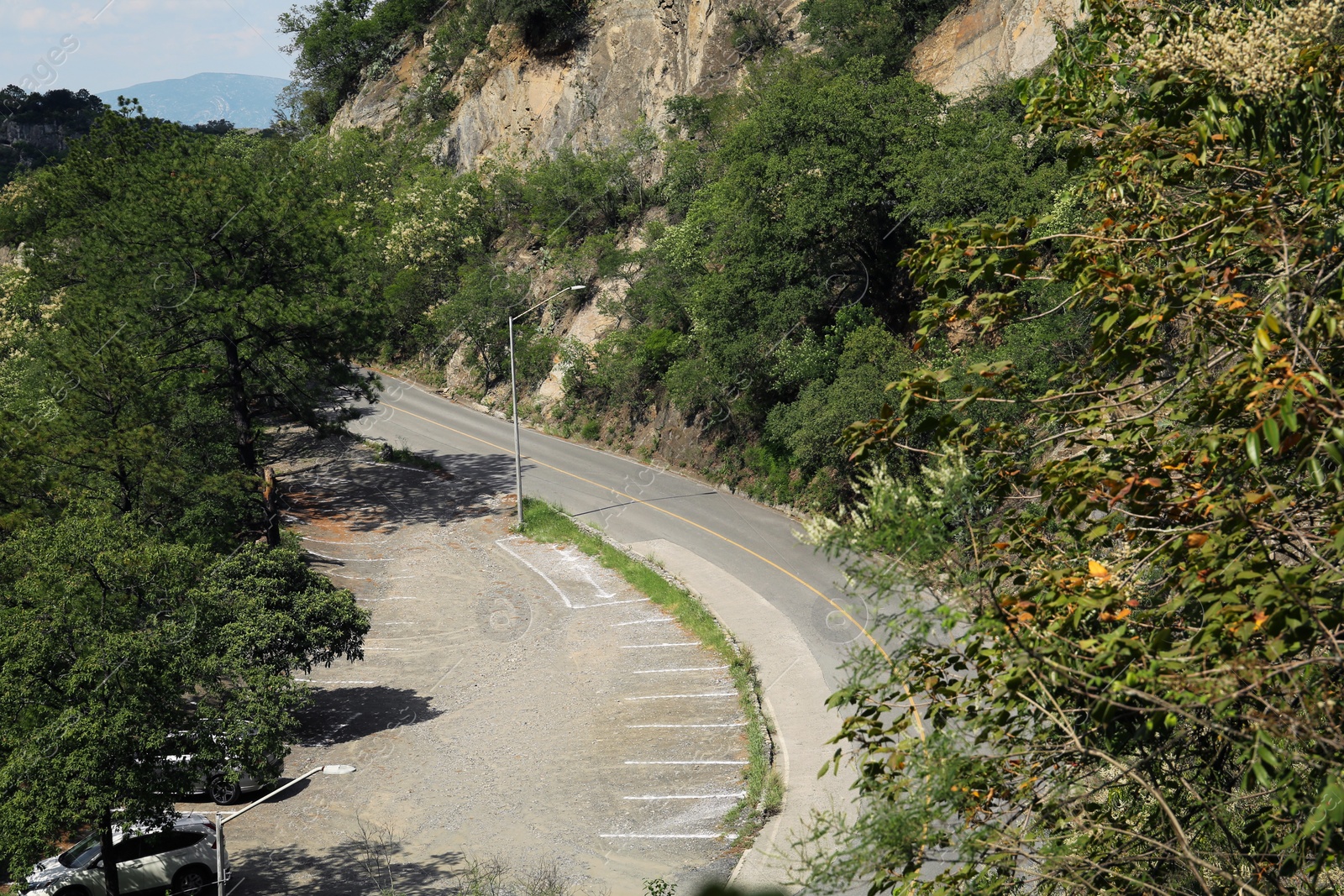 Photo of Road and parking lots with painted markings on asphalt near mountains outdoors