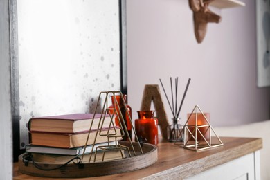 Wooden tray with books and decor on table indoors