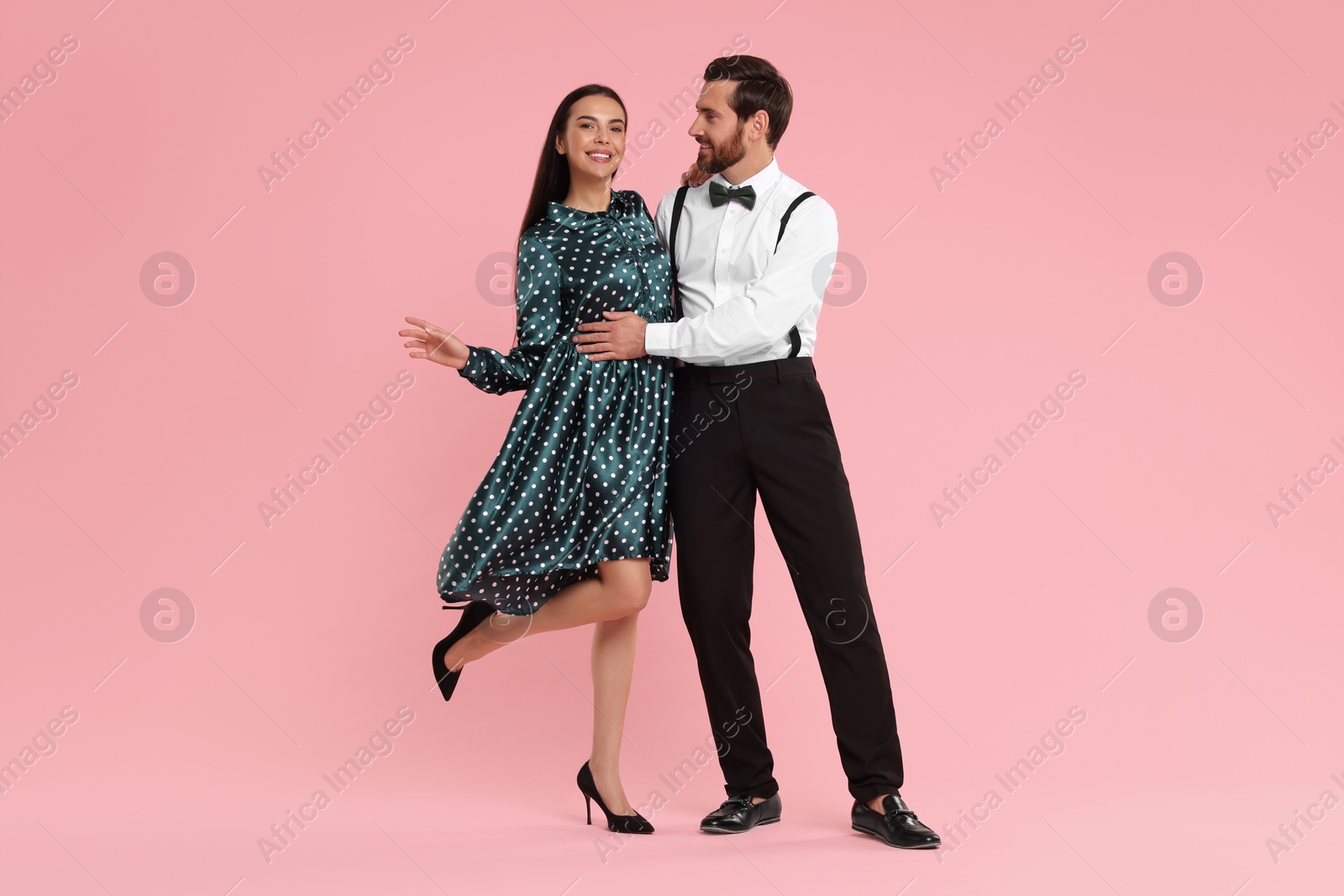 Photo of Happy couple dancing together on pink background