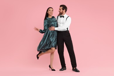 Happy couple dancing together on pink background