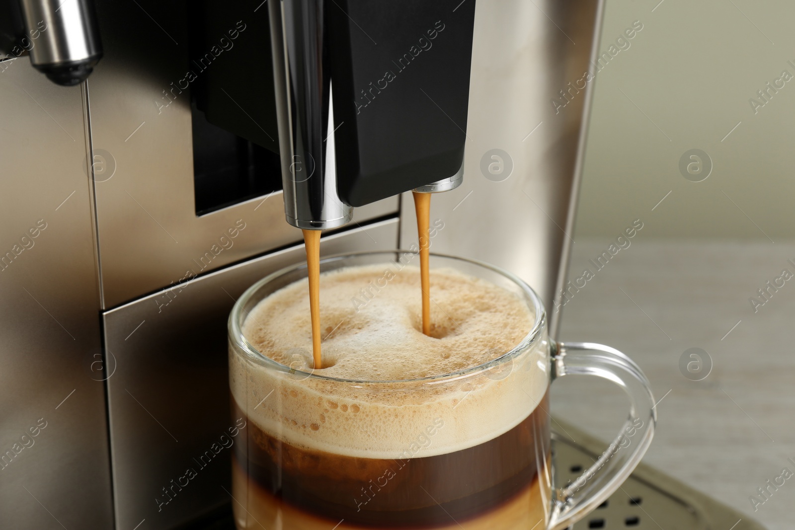 Photo of Modern coffee machine making latte into glass cup on wooden table, closeup