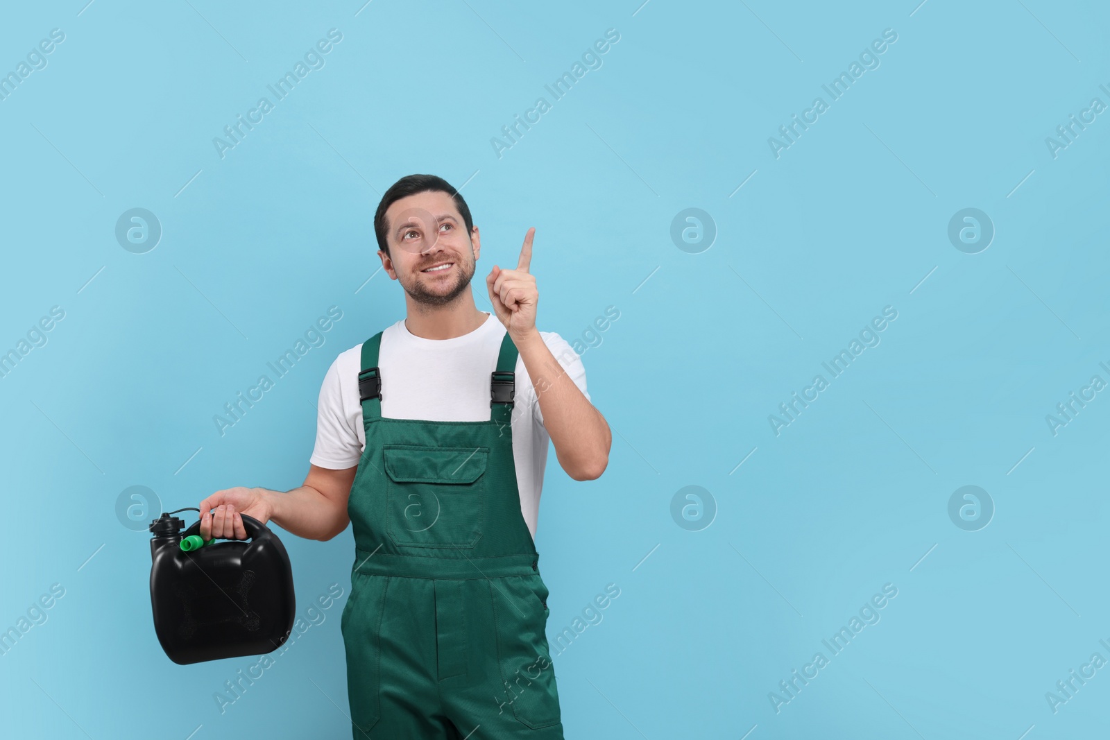 Photo of Man holding black canister and pointing at something on light blue background. Space for text