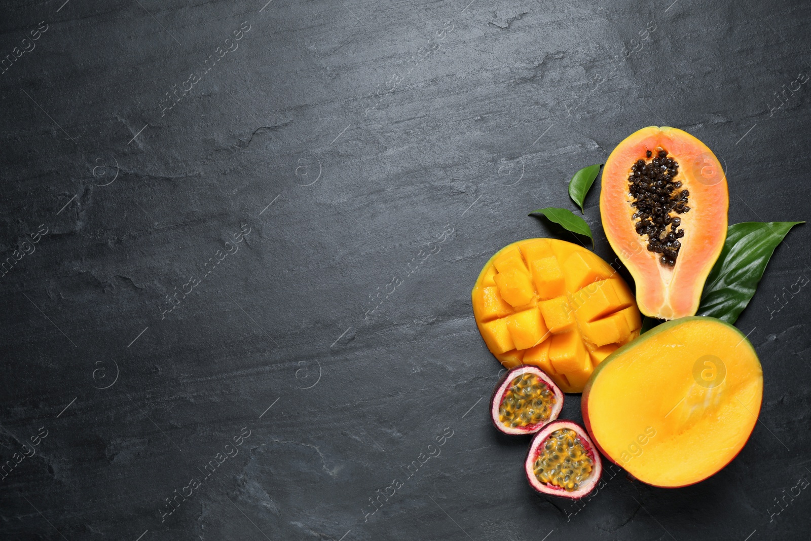 Photo of Fresh ripe papaya and other fruits on black table, flat lay. Space for text