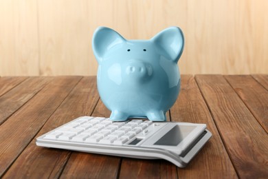 Calculator and piggy bank on wooden table