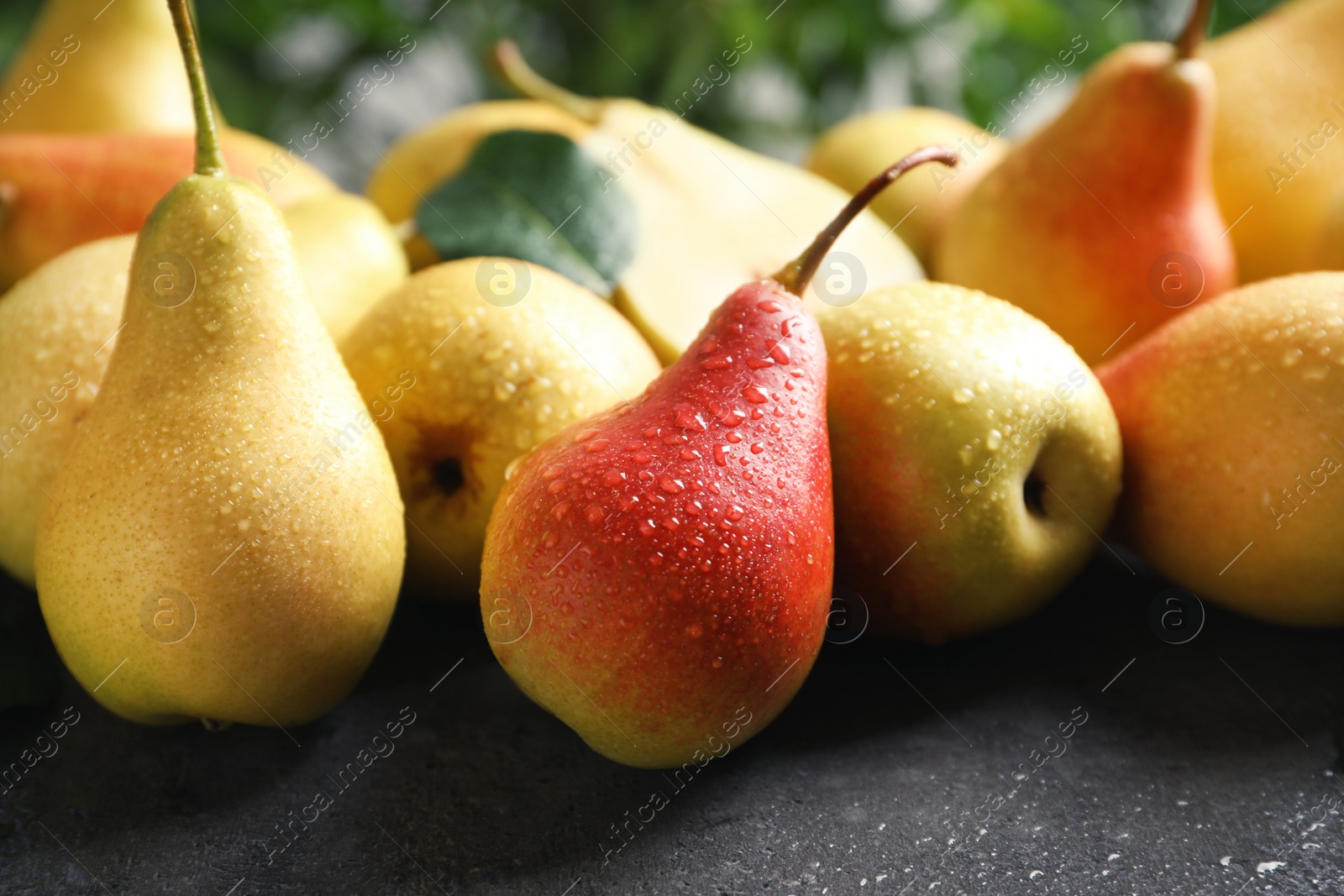 Photo of Ripe pears on grey table against blurred background