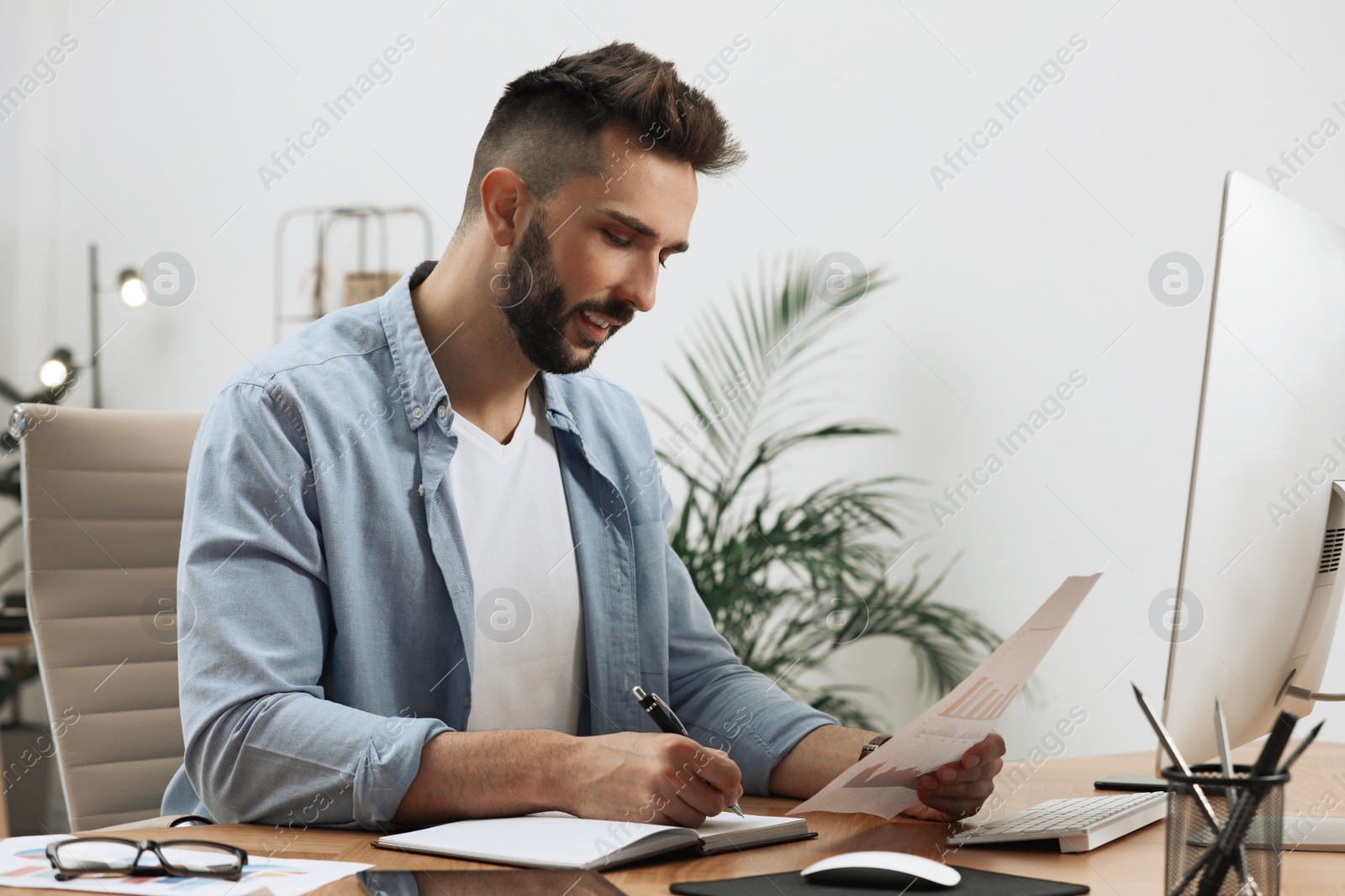 Photo of Man working with document at table in office
