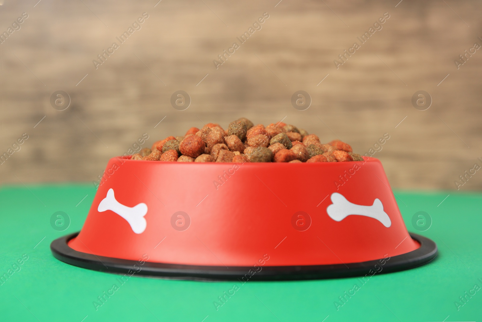 Photo of Dry dog food and feeding bowl on green table