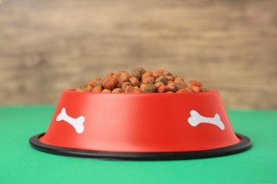 Dry dog food and feeding bowl on green table