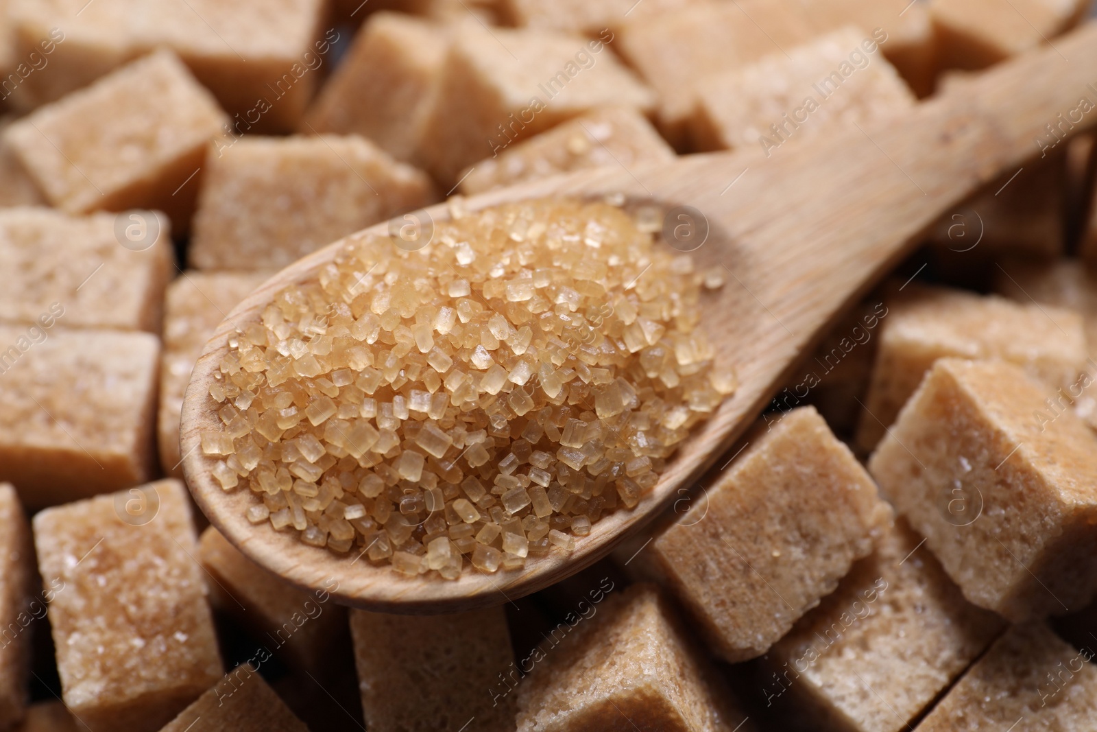 Photo of Wooden spoon on brown sugar cubes, closeup