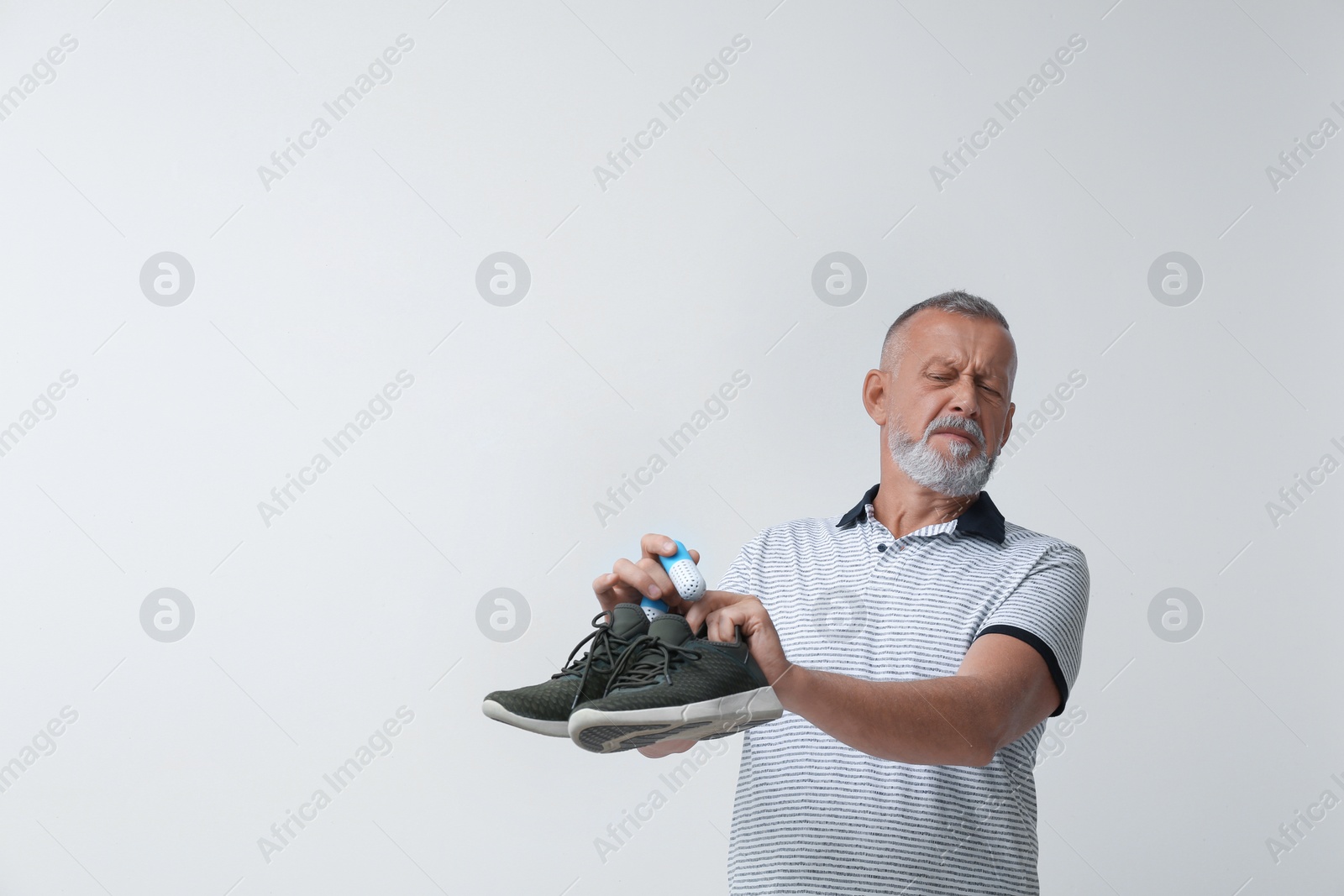 Photo of Man putting capsule shoe freshener in footwear on white background. Space for text