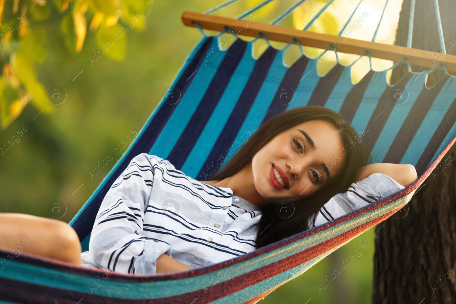 Photo of Young woman resting in comfortable hammock at green garden