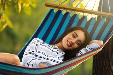 Young woman resting in comfortable hammock at green garden