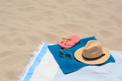 Blanket with blue towel and beach accessories on sand