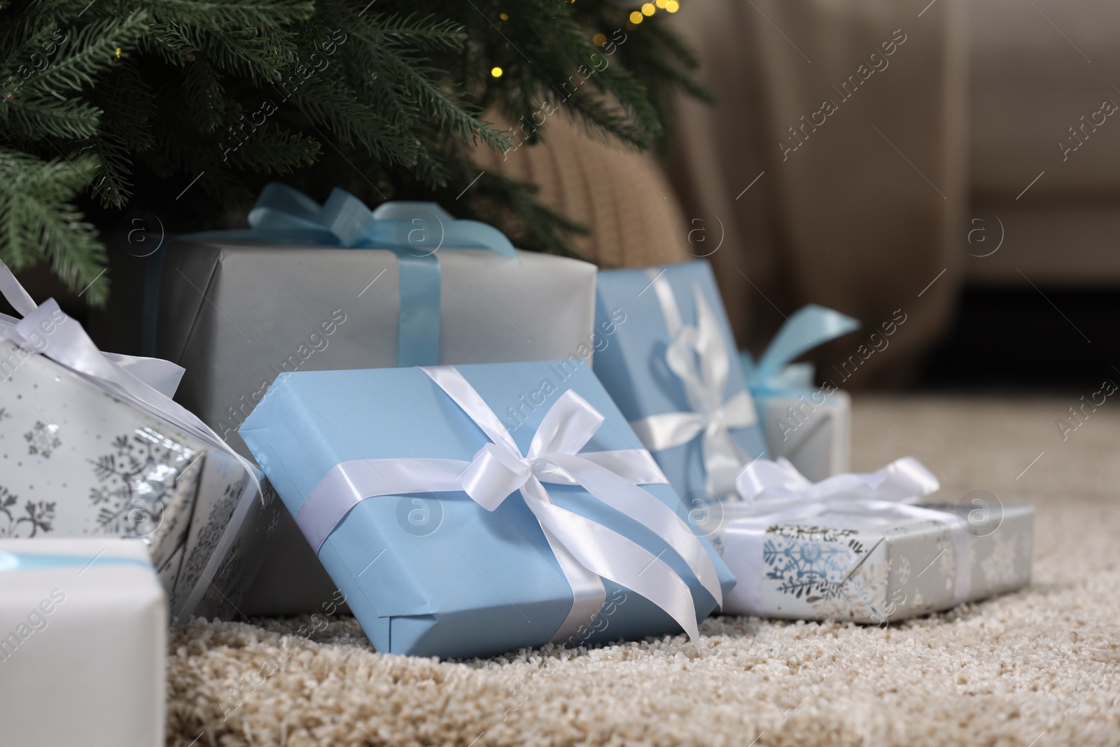 Photo of Many different gifts under Christmas tree on carpet indoors