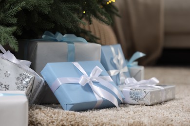 Many different gifts under Christmas tree on carpet indoors